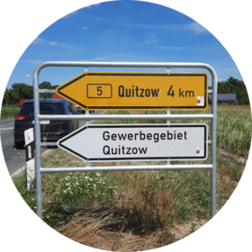 Straßenschild mit zwei Pfeilwegweisern mit der Beschriftung "Quitzow 4 km" und "Gewerbegebiet Quitzow"